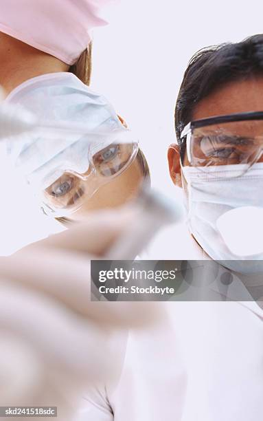 high angle view of a male dentist and female nurse holding dental tools - dentist phobia stock-fotos und bilder