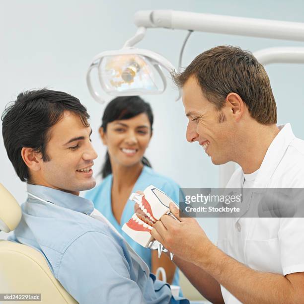 close-up of dentist and dental nurse showing patient how to wash teeth - how fotografías e imágenes de stock