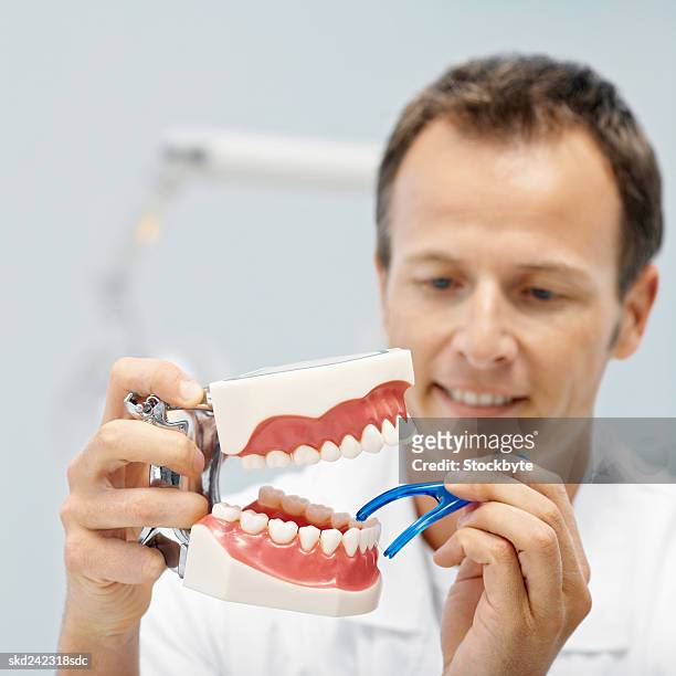 front view portrait of dentist demonstrating how to floss teeth with dental floss - how fotografías e imágenes de stock