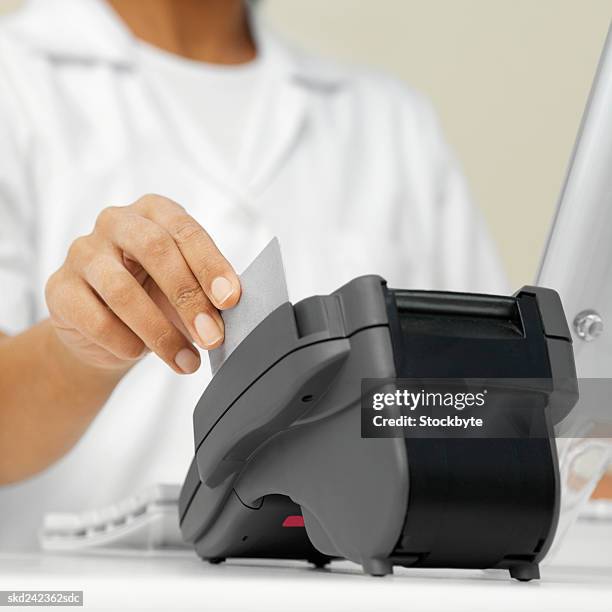 close-up mid section of dental nurse processing payment with credit card reader - e reader - fotografias e filmes do acervo