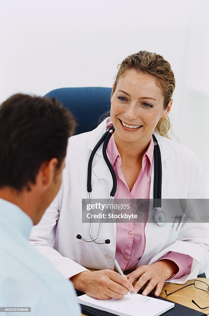 Portrait of a female doctor writing a prescription for a man