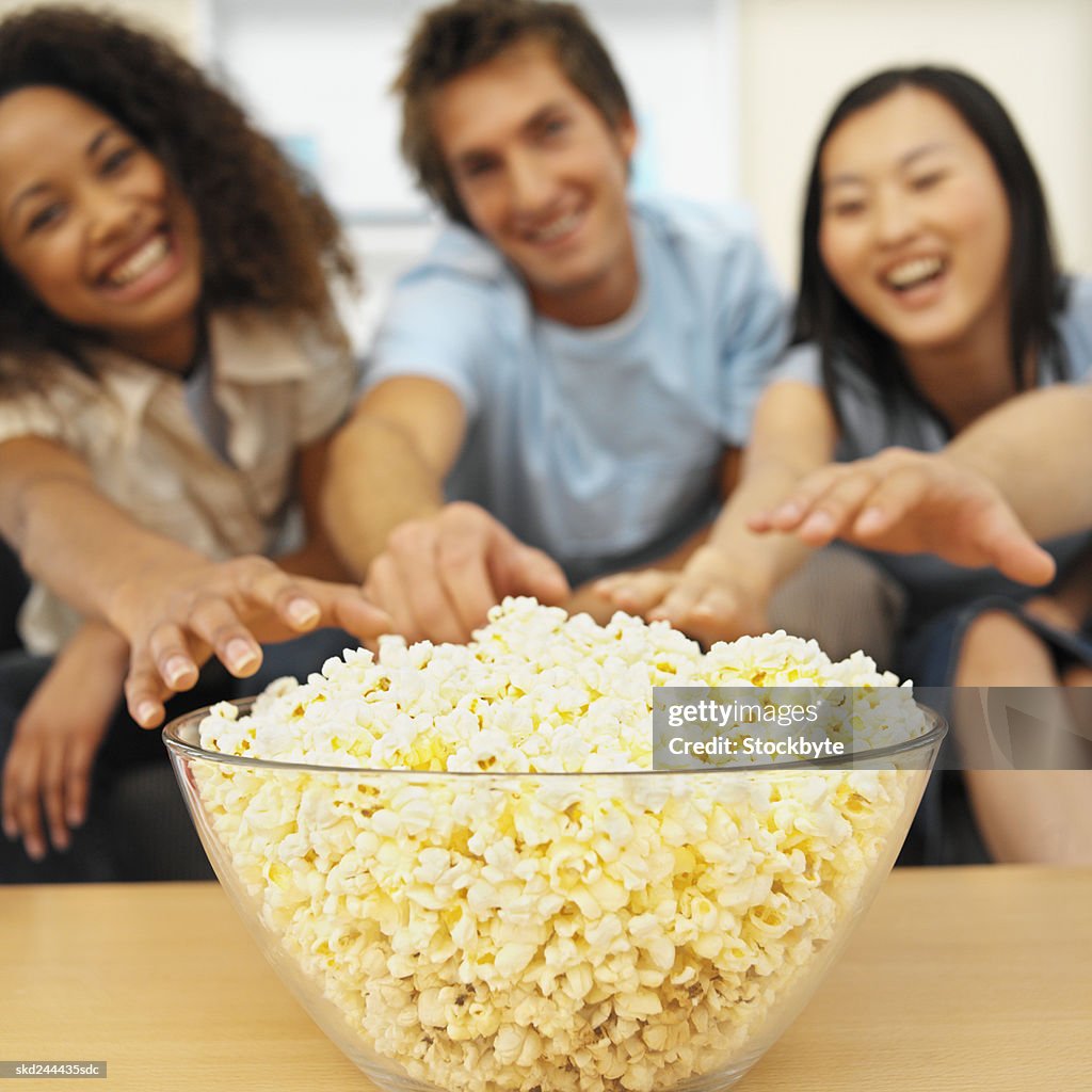 Close-up of three young people eating popcorn