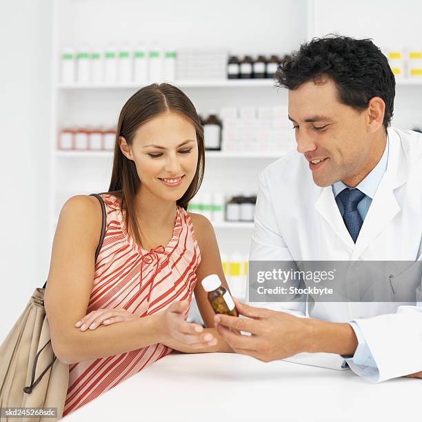 close-up of pharmacist and patient looking at container of medicine - close up counter ストックフォトと画像