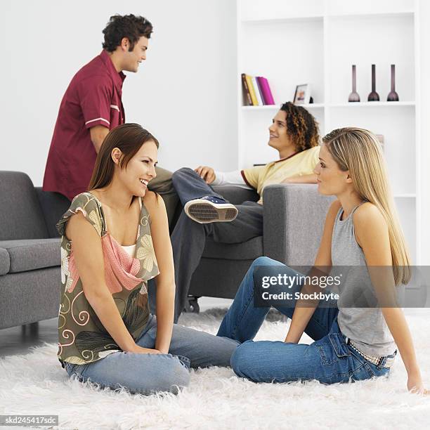 four young people sitting in living room relaxing - living stock-fotos und bilder