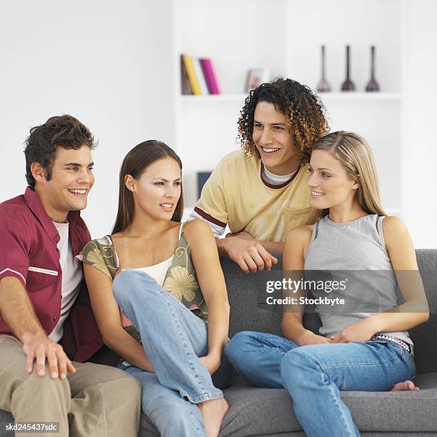 four young people sitting in living room relaxing - living stock-fotos und bilder