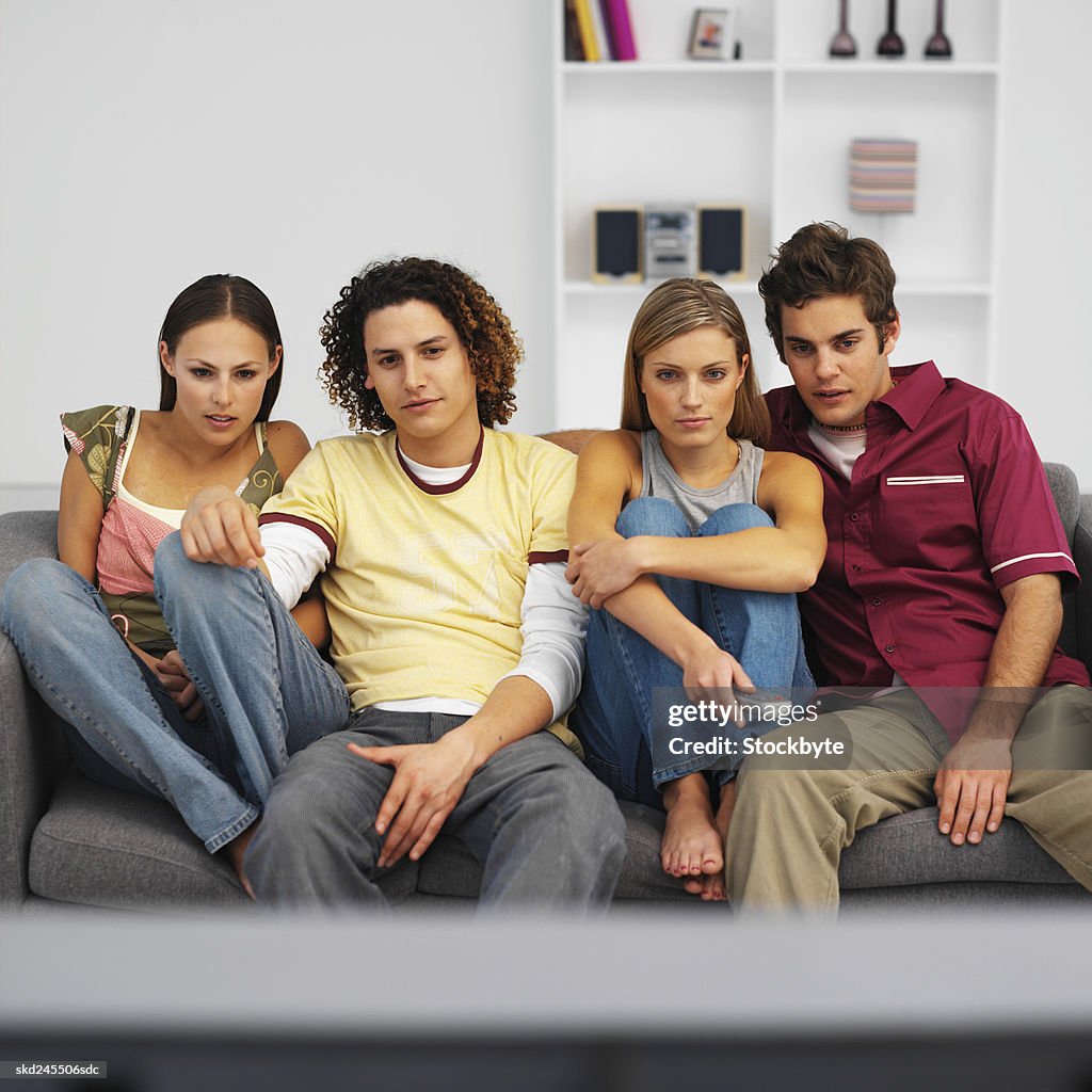 Front view of four young people watching television