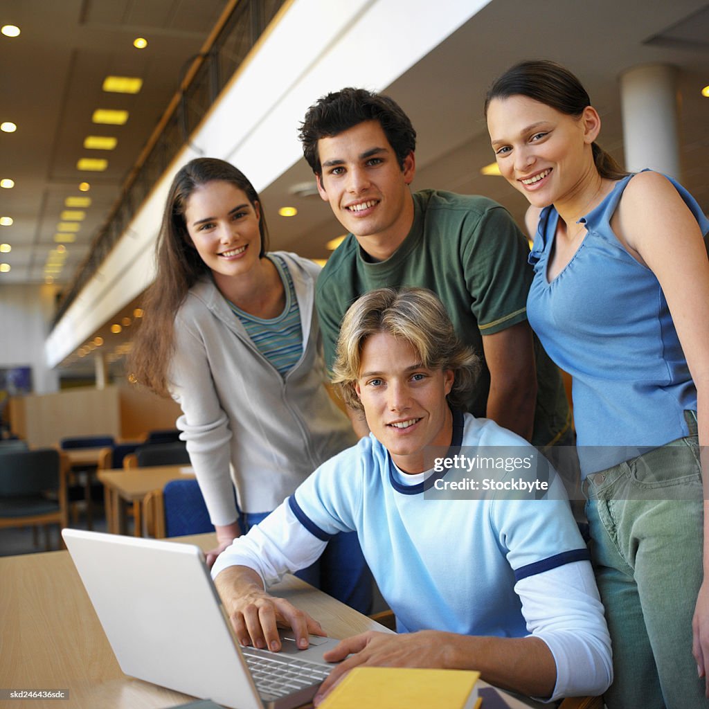 Close-up of four people working on laptop