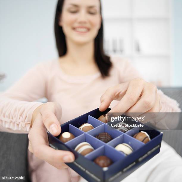 woman enjoying a box of chocolates - chocolate pieces stock-fotos und bilder