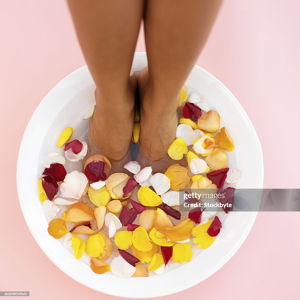 A woman's feet in a bowl of water and flower petals