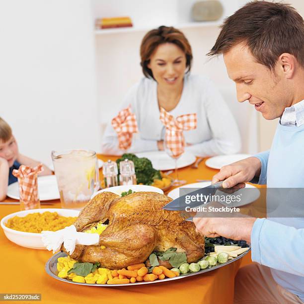 father carving a chicken at a family dinner - carvery stockfoto's en -beelden