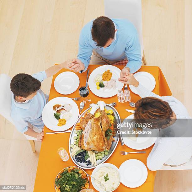 elevated view of a family saying grace - godsdienstvrijheid stockfoto's en -beelden
