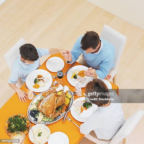 elevated view of a family saying grace - godsdienstvrijheid stockfoto's en -beelden