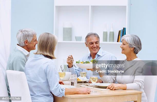 side profile of a mature woman serving a bowl of salad at a dinner table - side salad stock pictures, royalty-free photos & images