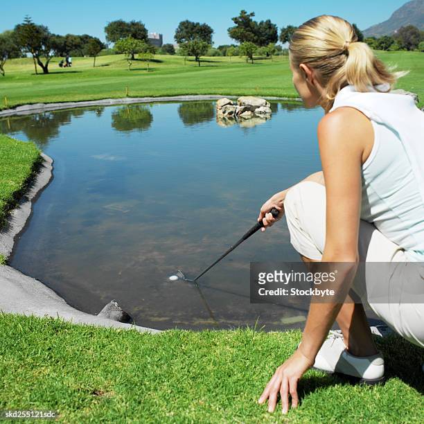 golfer trying to get golf ball from water - get stock pictures, royalty-free photos & images