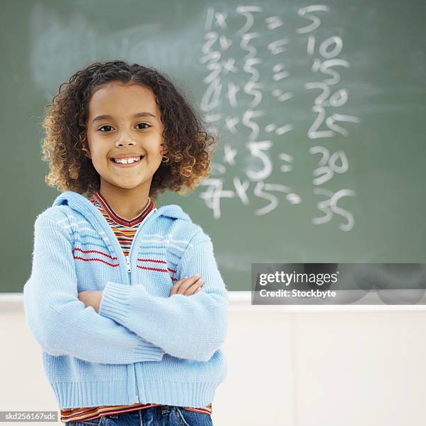 front view portrait of girl standing in front of chalkboard with arms crossed (8-9) - moltiplicazione foto e immagini stock
