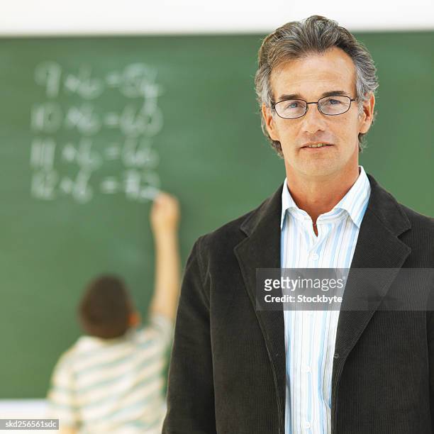 front view portrait of teacher and rear view of boy writing on chalkboard (10-11) - man rear view grey hair closeup stock pictures, royalty-free photos & images