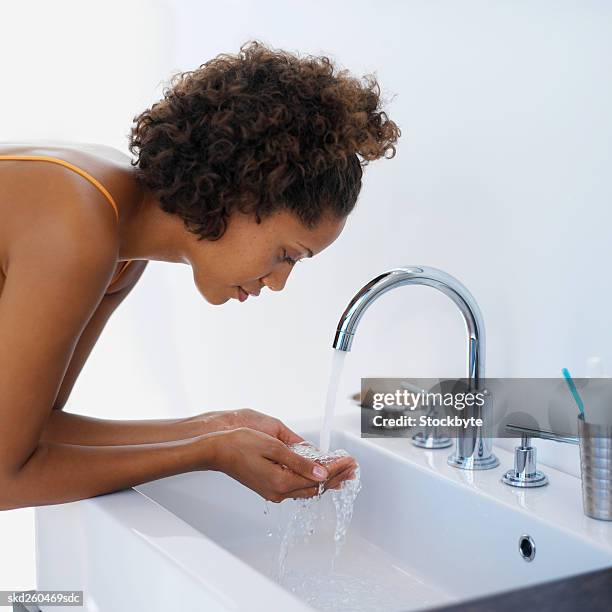 side view of a woman running water into her hands about to wash her face - about stock pictures, royalty-free photos & images