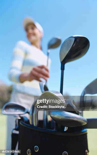 low angle view of a woman removing a golf club from a bag (blurred) - golf club - fotografias e filmes do acervo