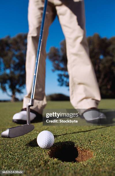 close-up of a man holding a golf club against a golf ball - golf club - fotografias e filmes do acervo