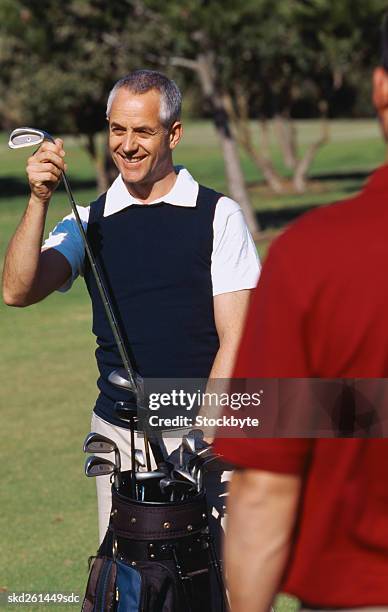 portrait of a mature man removing a golf club from a bag - golf club - fotografias e filmes do acervo