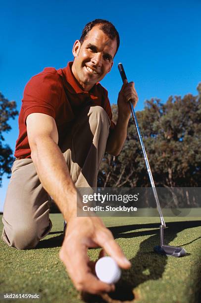 low angle view of smiling golfer removing his ball from the hole after a successful putt - after stock pictures, royalty-free photos & images