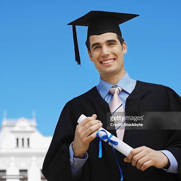front view portrait of young man wearing cap and gown and holding certificate - 2005 20 stock pictures, royalty-free photos & images