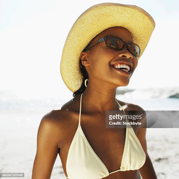 front view portrait of young woman wearing sunglasses and sun hat - hat stock-fotos und bilder