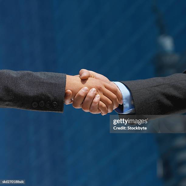 low angle view of a handshake between a businessman and businesswoman - between stock-fotos und bilder