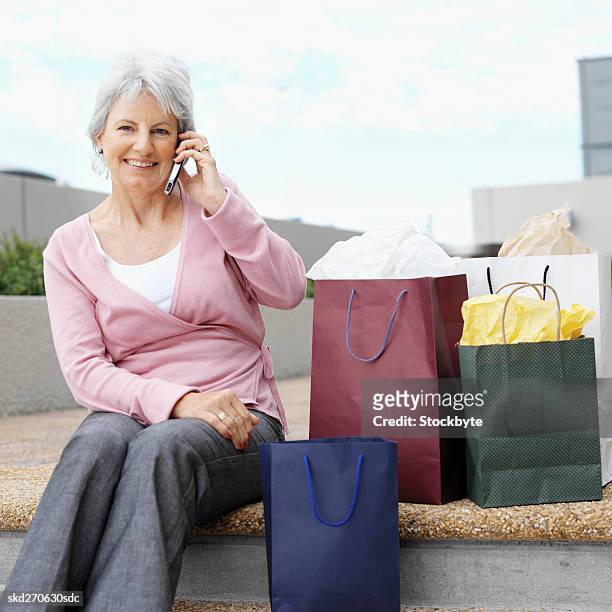 close-up front view of senior woman talking on mobile phone with shopping bags beside him - square neckline fotografías e imágenes de stock