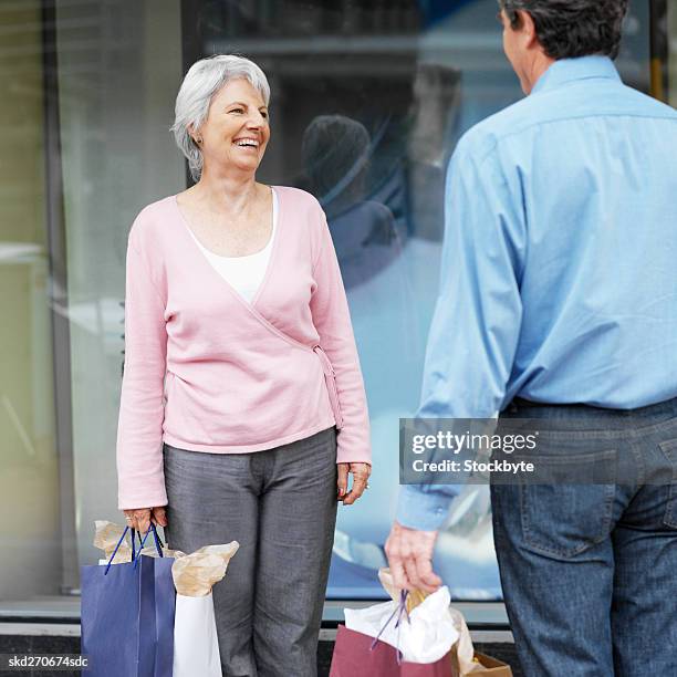 senior couple standing in street holding shopping bags - square neckline 個照片及圖片檔