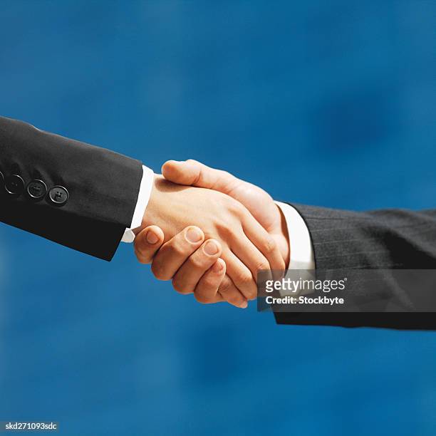 low angle close-up of a handshake between a businessman and businesswoman - between stock-fotos und bilder