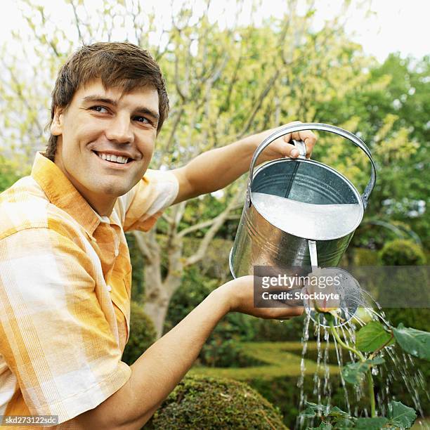 man watering plants - pitorro fotografías e imágenes de stock