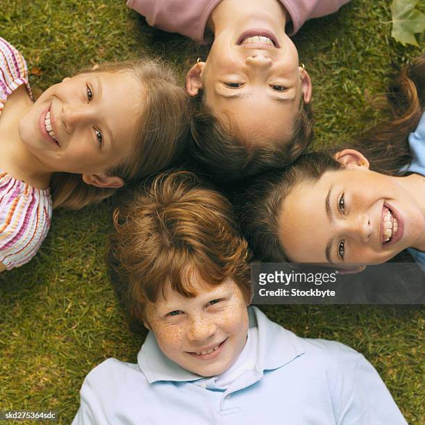 close-up of four children lying on grass with heads together (8-12) - happy tween girls lying on grass stock pictures, royalty-free photos & images