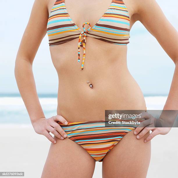 close-up mid section of a woman standing at beach - belly ring stock pictures, royalty-free photos & images