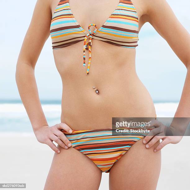close-up mid section of a woman standing at beach - piercing de umbigo - fotografias e filmes do acervo