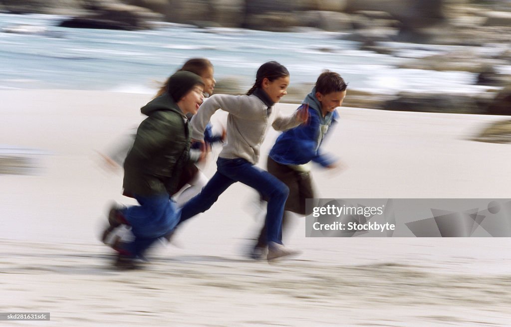 Four children running on the beach