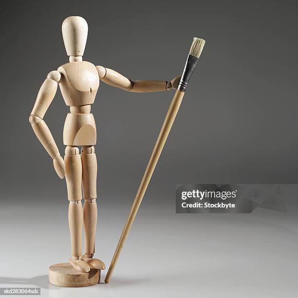 artist's mannequin holding a paint brush - modell stockfoto's en -beelden