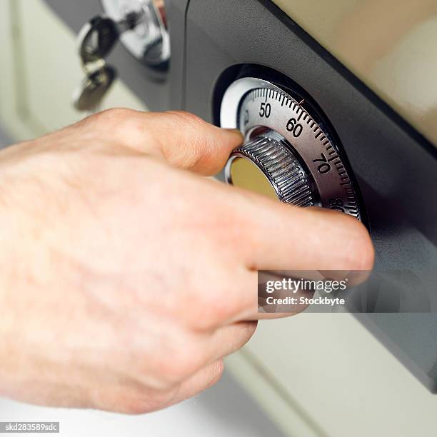 elevated view of man's hand turning combination lock of safe - beschützer stock-fotos und bilder