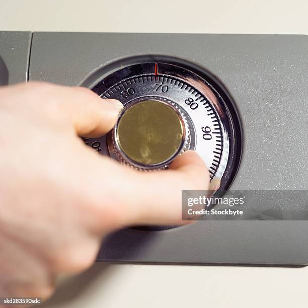 elevated view of man's hand turning combination lock of safe - beschützer stock-fotos und bilder