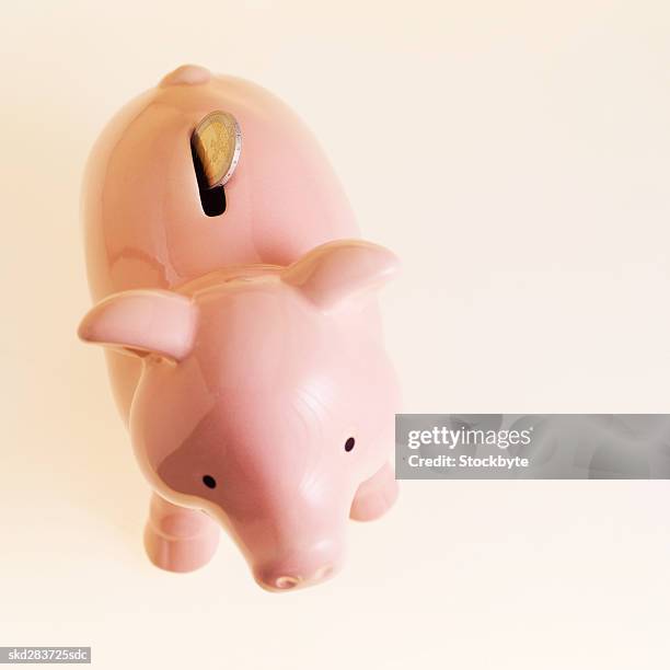 close-up of a piggy bank with a two euro coin sticking out of top - zwei euro münze stock-fotos und bilder