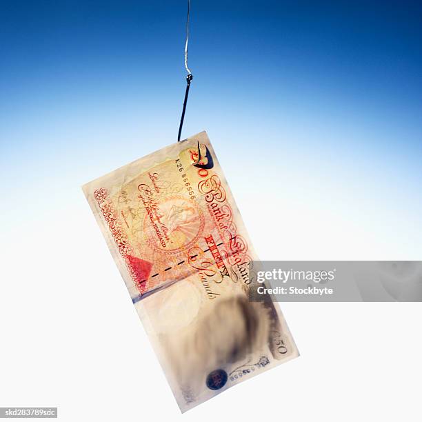 close-up of an english fifty pound note hanging on fishhook - 50 pound notes stock pictures, royalty-free photos & images
