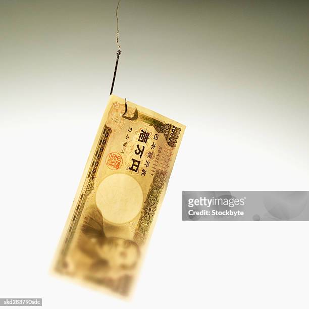 close-up of ten thousand yen note hanging on fishhook - ten thousand yen note stock pictures, royalty-free photos & images