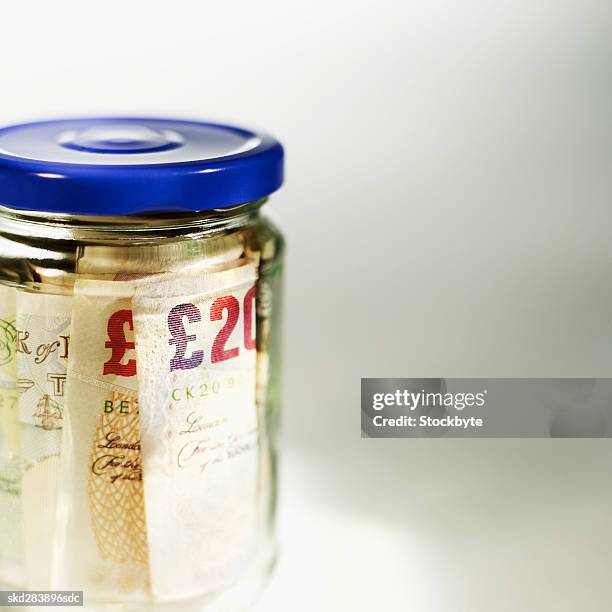 close-up of a jar containing u.k.. pound notes - twenty pound note stock pictures, royalty-free photos & images