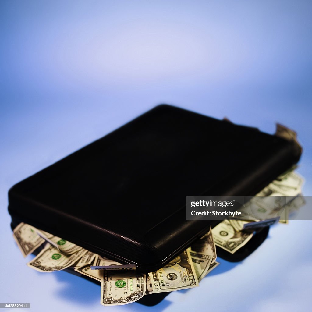 Elevated view of a briefcase overflowing with American dollar bills
