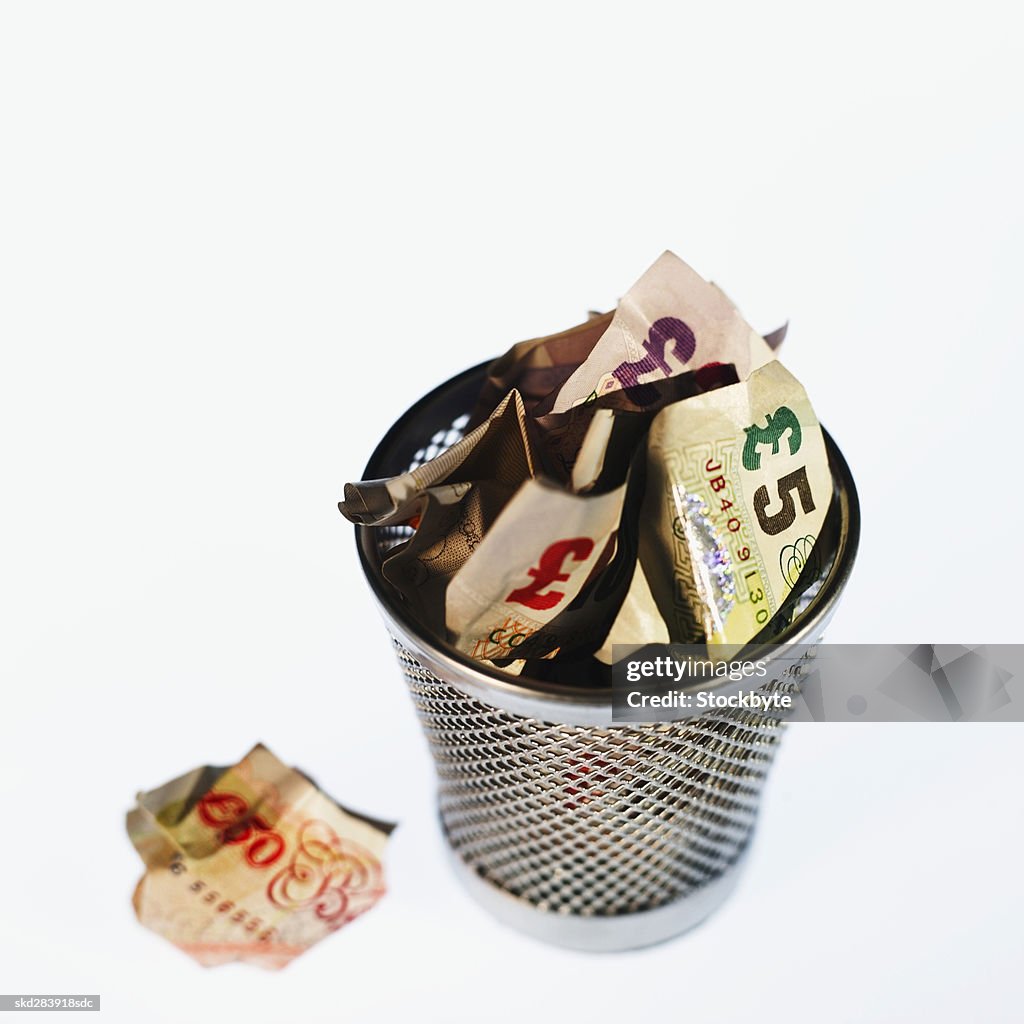 Elevated view of crumpled U.K.. pound notes in rubbish bin