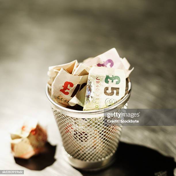 elevated view of crumpled u.k.. pound notes in rubbish bin - ten pound note stock pictures, royalty-free photos & images