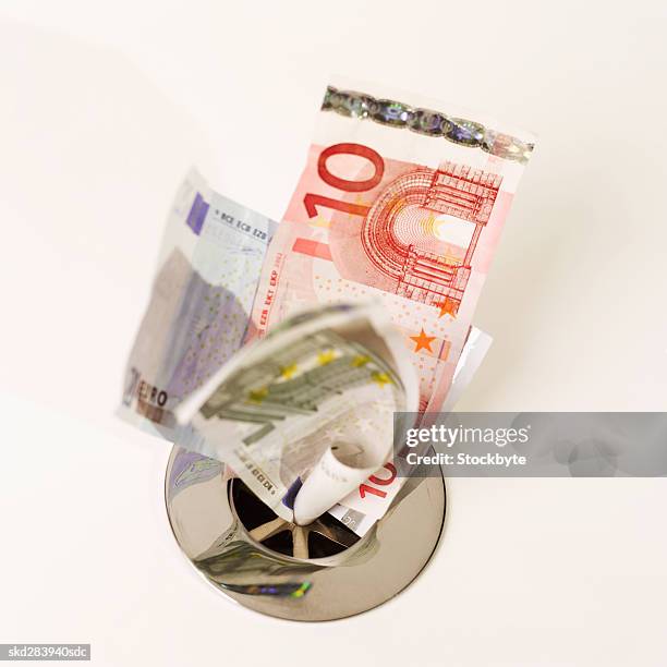 close-up of euro bank notes going down the drain - twenty euro note stock pictures, royalty-free photos & images