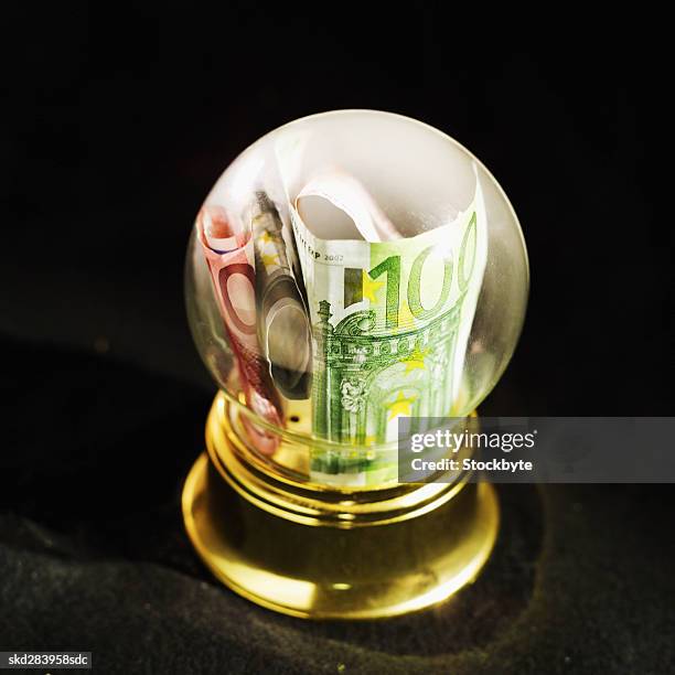 close-up of snow globe containing euro bank notes - billet de 5 euros photos et images de collection