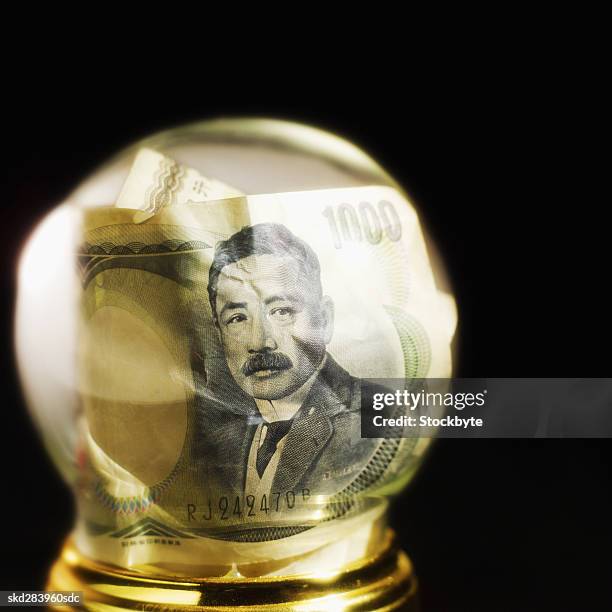 close-up of snow globe containing japanese yen bank notes - all asian currencies stock pictures, royalty-free photos & images