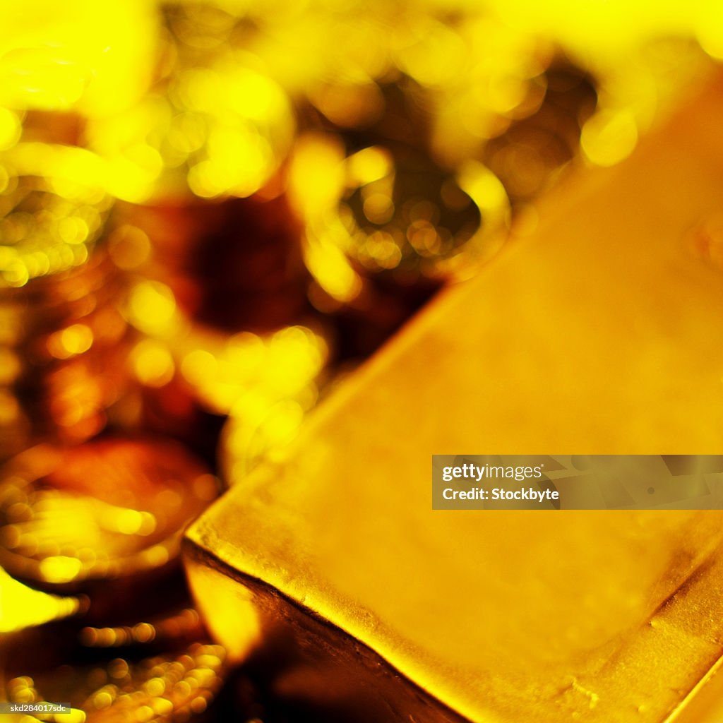 Close-up of a stack of gold bars and currency coins